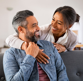 Pareja sonriendo sentados en la sala de su casa